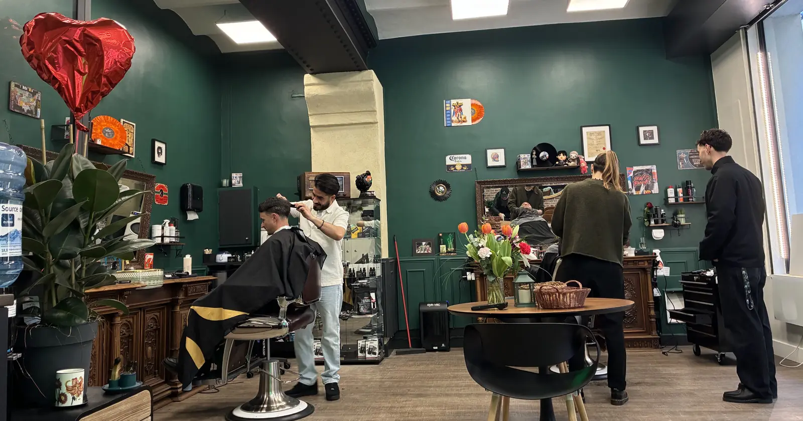 Vue d'ensemble du salon CALM à Montpellier : deux postes de coiffage, murs vert bouteille et parquet.
